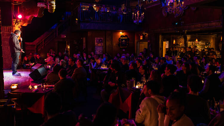 A large crowd of people watches a comedian on stage.