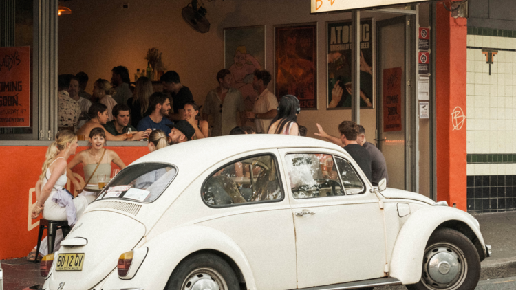 People spilling out on street at a bar 