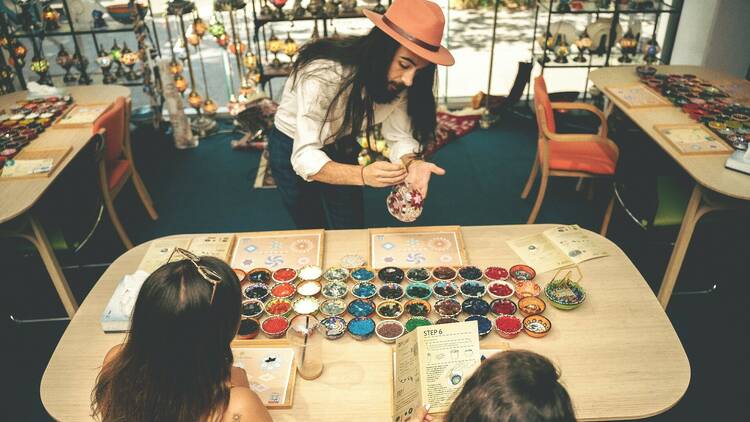 A man teaches two girls about Turkish glass.