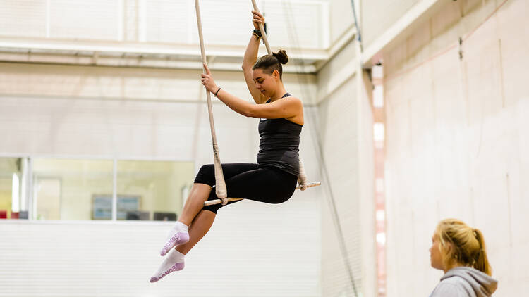 A person sits on a trapeze.