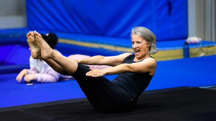 A woman with grey hair does a v-snap strength exercise.