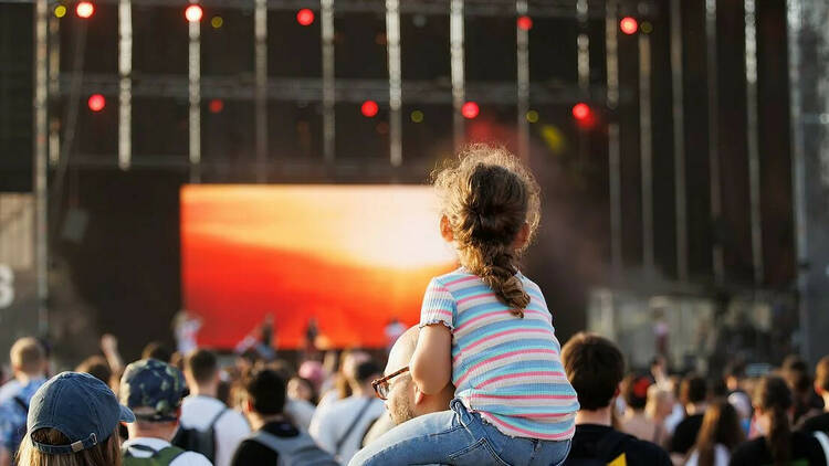 Imagen de una niña a hombros de un adulto viendo un concierto del festival Primavera Sound