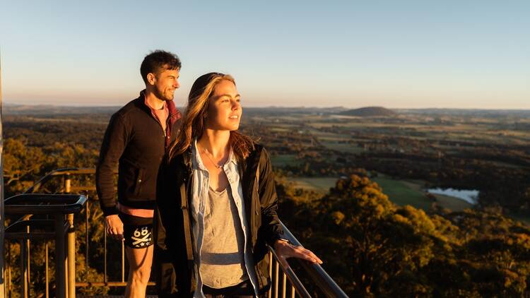 Two people enjoying the view from the Mount Buninyong lookout at sunset