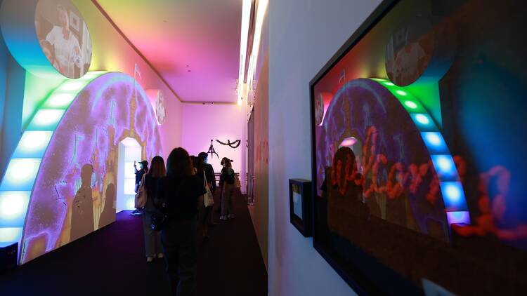 A rainbow-lit room featuring artworks by Banksy.