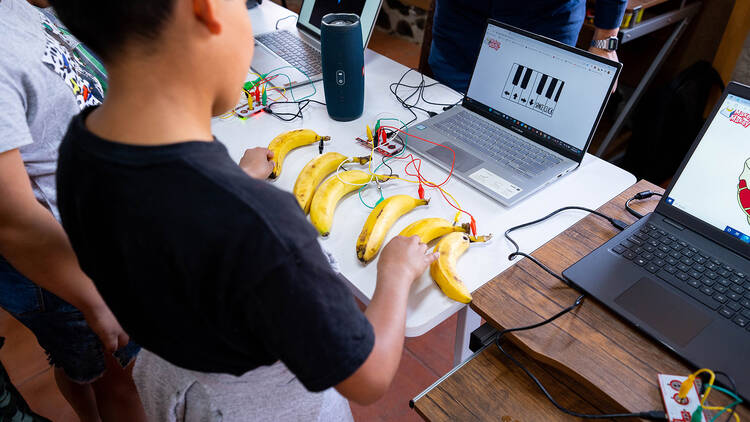 Niño haciendo música con plátanos ayudándose de la energía eléctrica