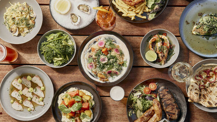 A flatlay of a variety of gourmet pub meals and drinks on a wooden table 