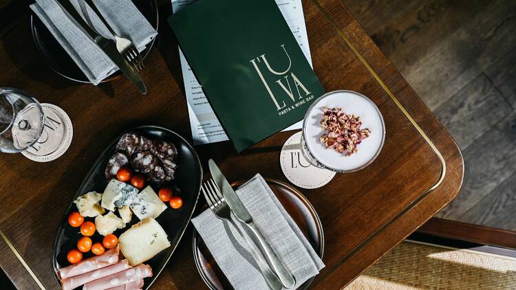 Antipasti on a table, shot from above, next to a glass of wine and cocktail.