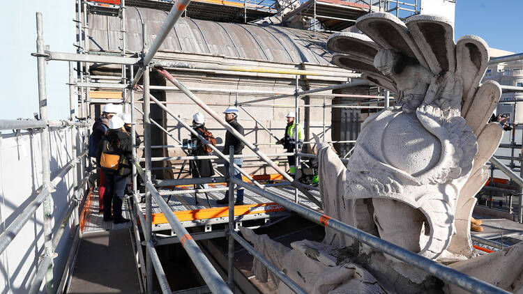 Varias personas durante su recorrido por los andamios que rodean la Puerta de Alcalá que permite ver las grandes esculturas que forman parte de este icono de Madrid