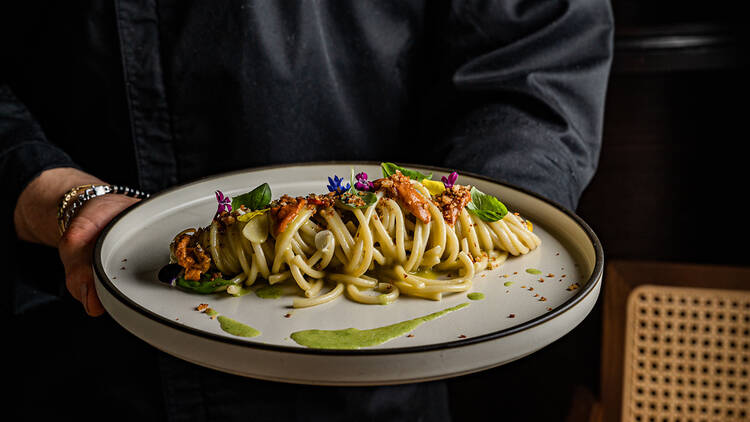 A person holding a plate of pasta.