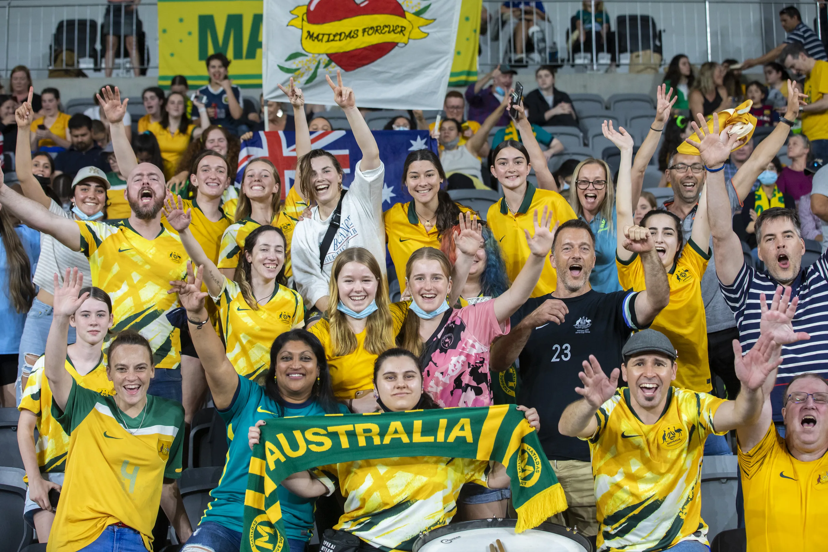 A crowd wearing green and Gold cheers on the Matildas football team.
