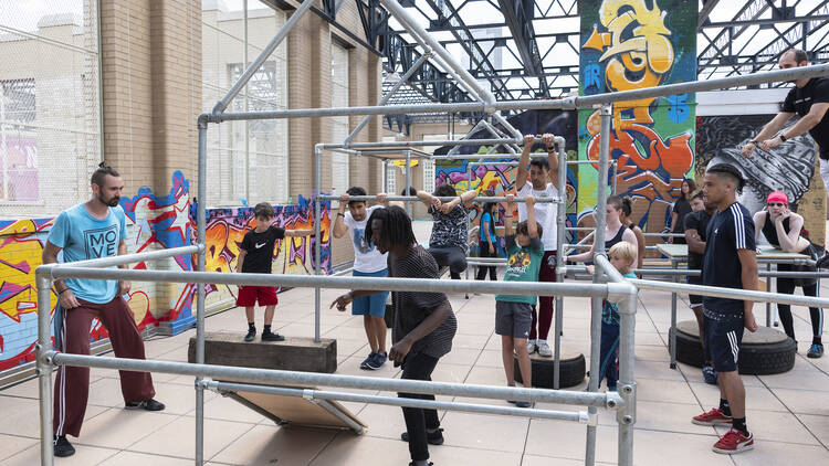A group of people climb on bars while practicing parkour.