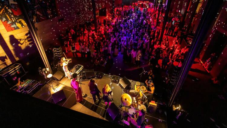 Aerial shot of the crowd at NGV Friday Nights bathed in red and blue lights.