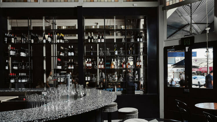 A dark and moody wine bar with shelves of wine.