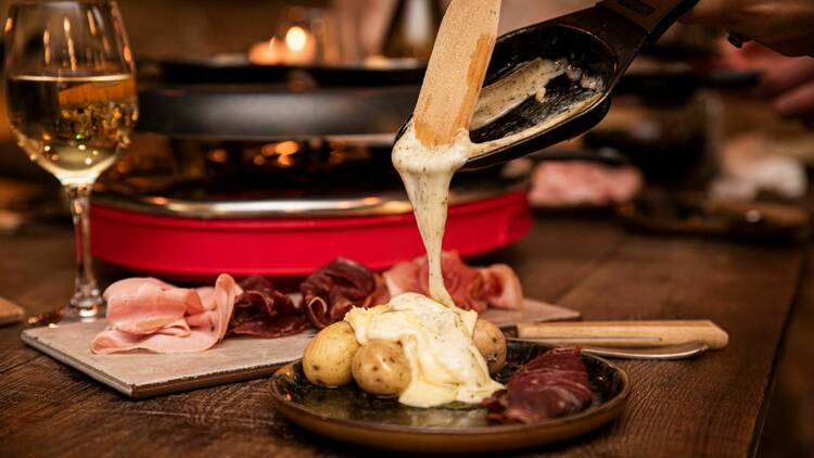 Melted raclette on top of boiled potatoes with cured meat and champange