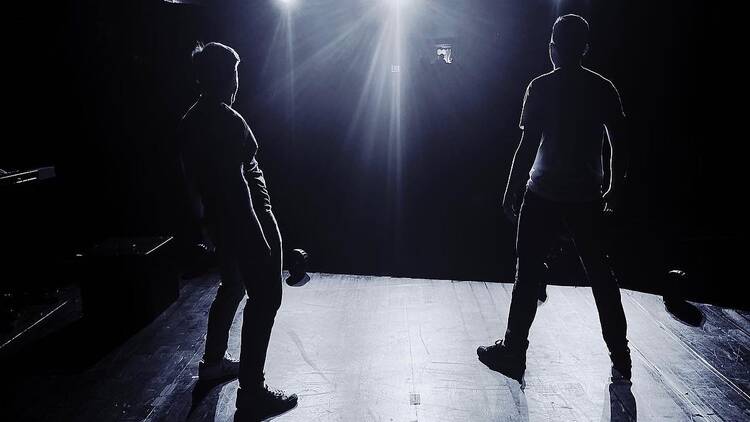 Two performers silhouetted on a stage.