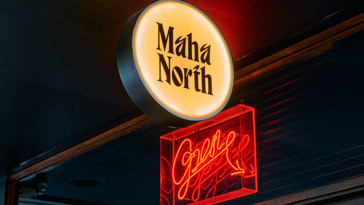 Circular Maha North sign lit up above red neon sign.