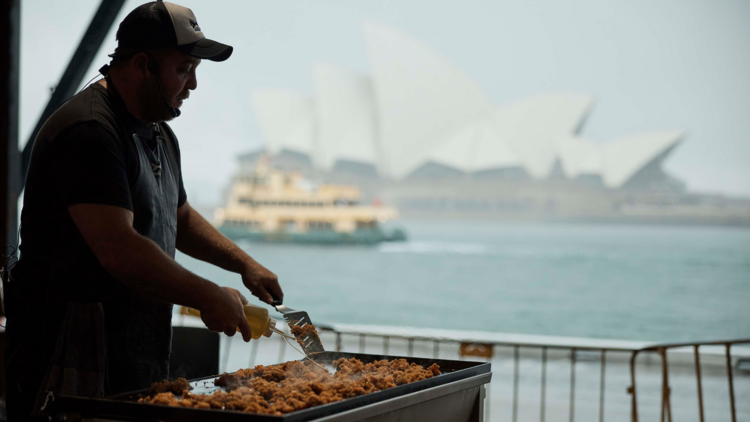 Indigenous chef barbecuing with a view of the Opera House