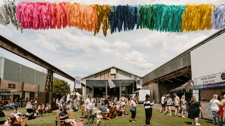 An outdoor market setting with food trucks and colourful bunting.