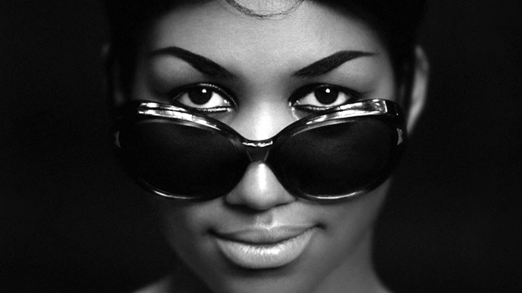 An old black and white photo shows Aretha Franklin wearing dark sunglasses