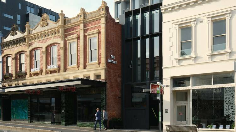 The heritage facade of the Motley Hotel with a tram passing.