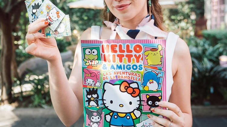 Álbum y estampas de Hello Kitty sostenidos por una persona