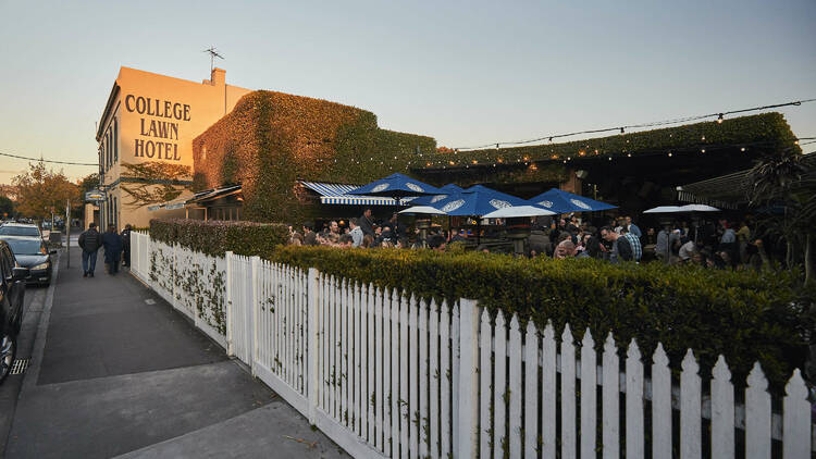 Street view of College Lawn Hotel pub and adjoining beer garden bordered by a white picket fence.