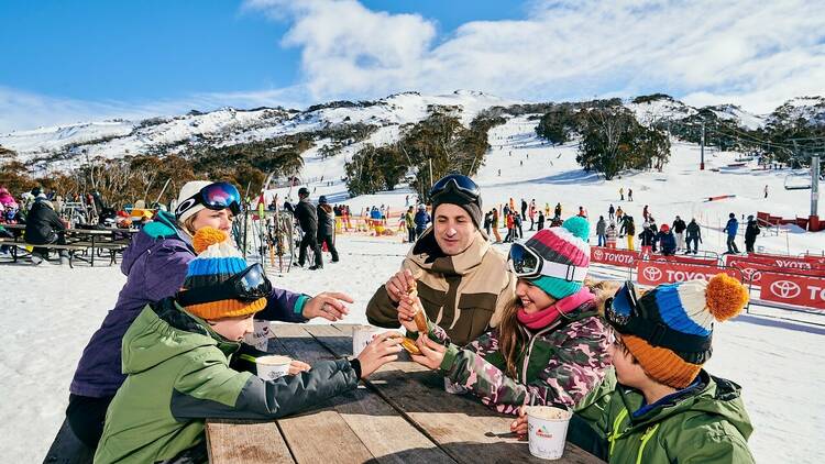 A family five warming up with hot chocolate at a Thredbo ski resort