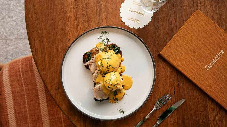 Plates of lobster Florentine with hollandaise sauce and an orange menu on a wooden table 