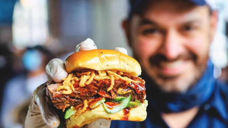 A chef holds up a brisket sandwich.