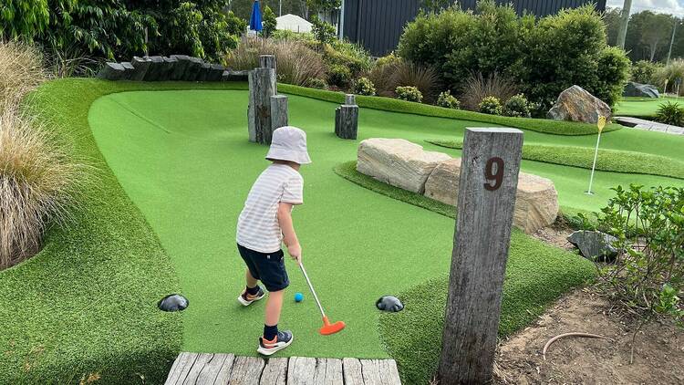 A child playing mini-golf