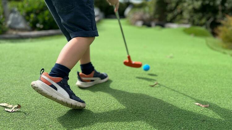 A child playing mini-golf