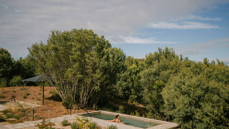 A person bathes in an outdoor thermal springs pool.