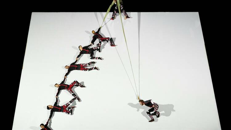 Six dancers hold hands dangling on a deep slope 