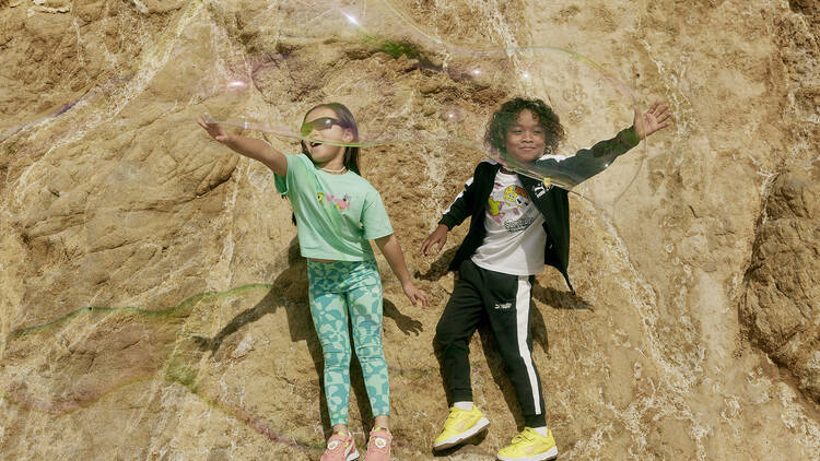 Dos niños en una montaña jugando con una burbuja y usando la colección Puma y Bob esponja