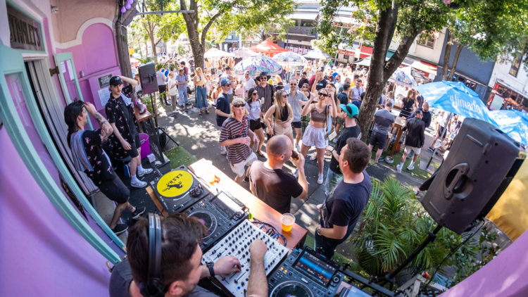 A DJ at a street party with a large crowd