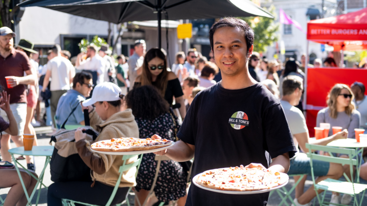 A waiter holding two pizzas