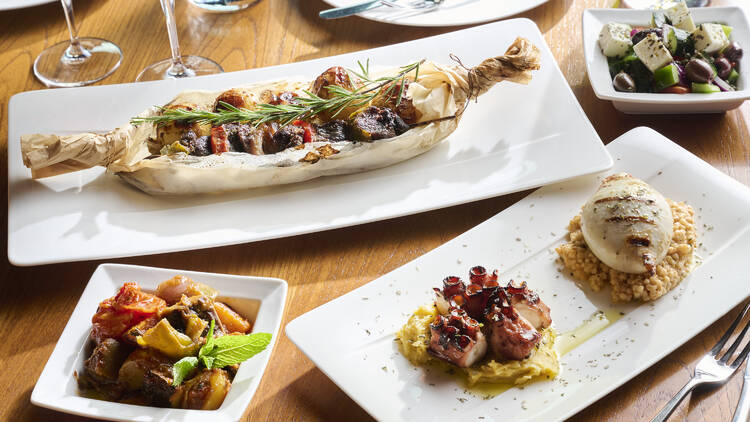 Assorted plates of Greek food laid out on a table