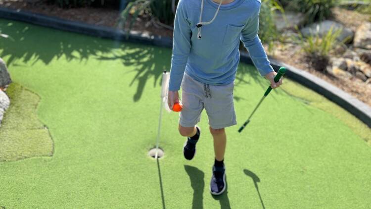 A child playing mini golf