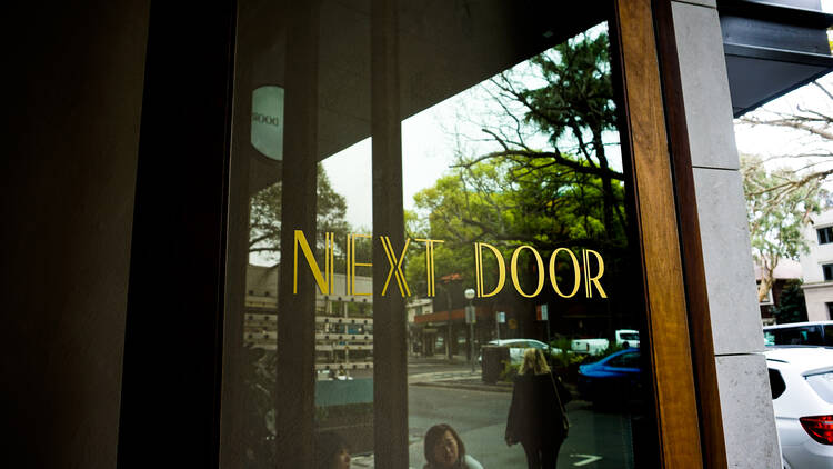 The outside door and sign at Next Door
