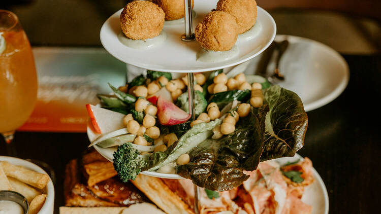 Multi-tiered platter of meat, cheese, vegetables and other snacks.