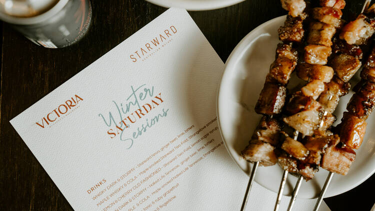 Plate of meat skewers placed partly on top of a menu.