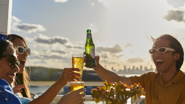 Three people clinking beers in the sun