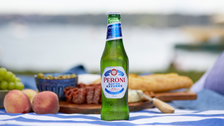 A beer on a picnic rug with a cheese platter