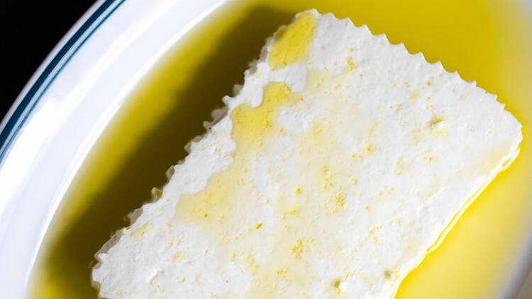 Ricotta drizzled in oil on a plate.