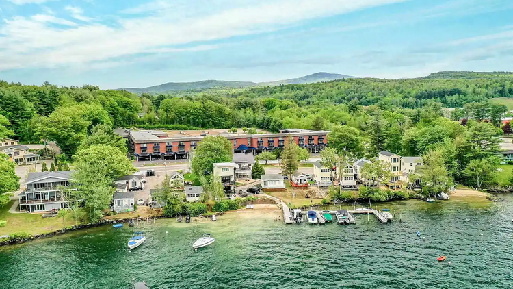Aerial view of a greenish bay with boats plying the water and condominiums perched right by the shore