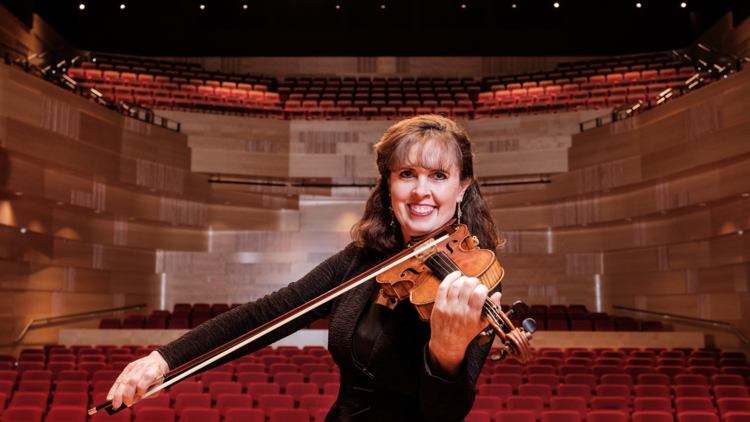 A woman violinist smiling in a concerthall