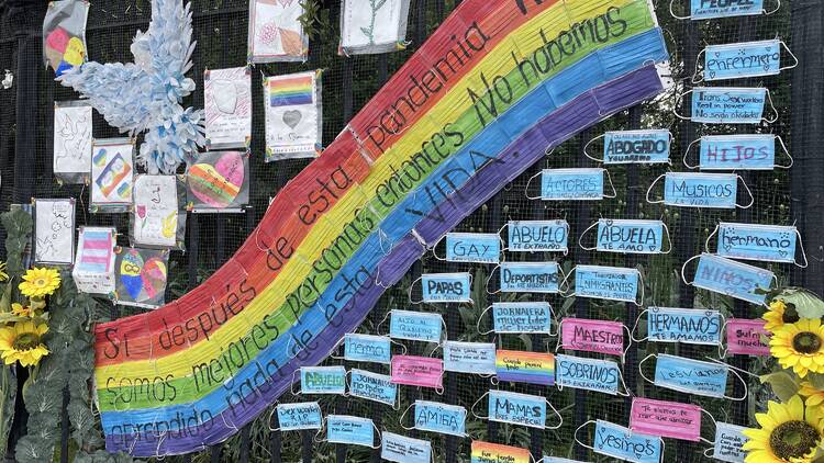 A rainbow sign and masks decorated with people's names.