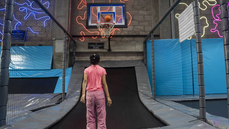 Niña lanza balón de básquetbol a tablero en Vaunce Jump