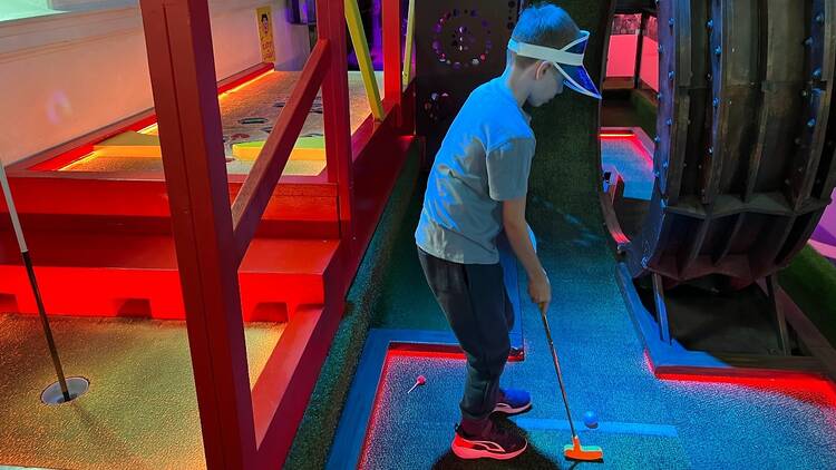 A child playing indoor mini golf