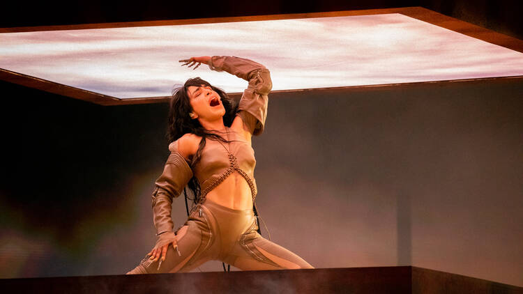 Loreen singing with her hand on a lit up square